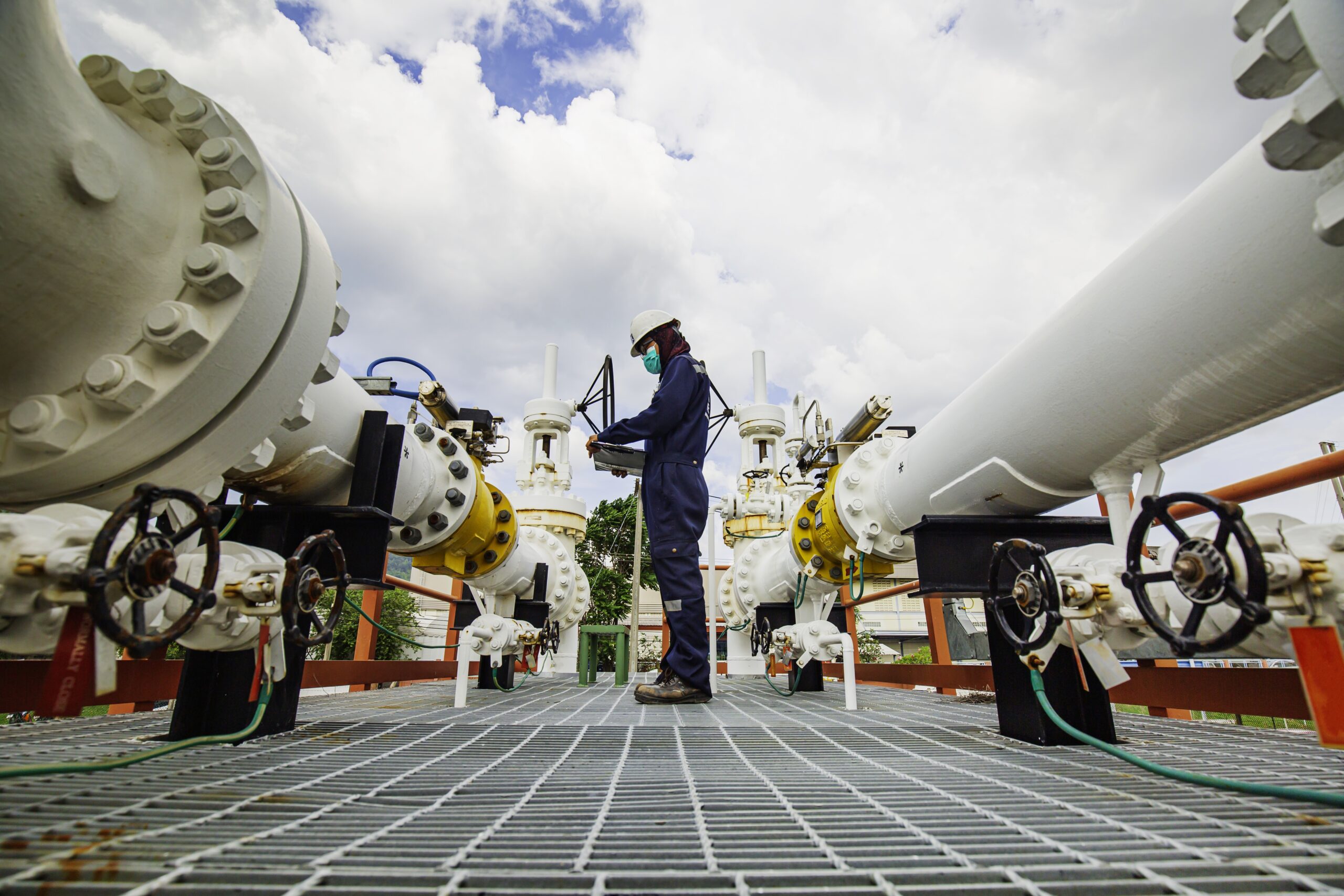 Male worker inspection at steel long pipes and pipe elbow in station oil factory during refinery valve of visual check record pipeline oil and gas industry.